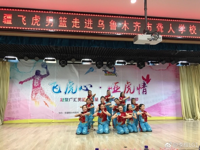 李根弯下腰,手把手地指导一名聋人学校的学生运球,孩子学得极其认真,眼神中充满了对篮球的热爱和对偶像的崇拜