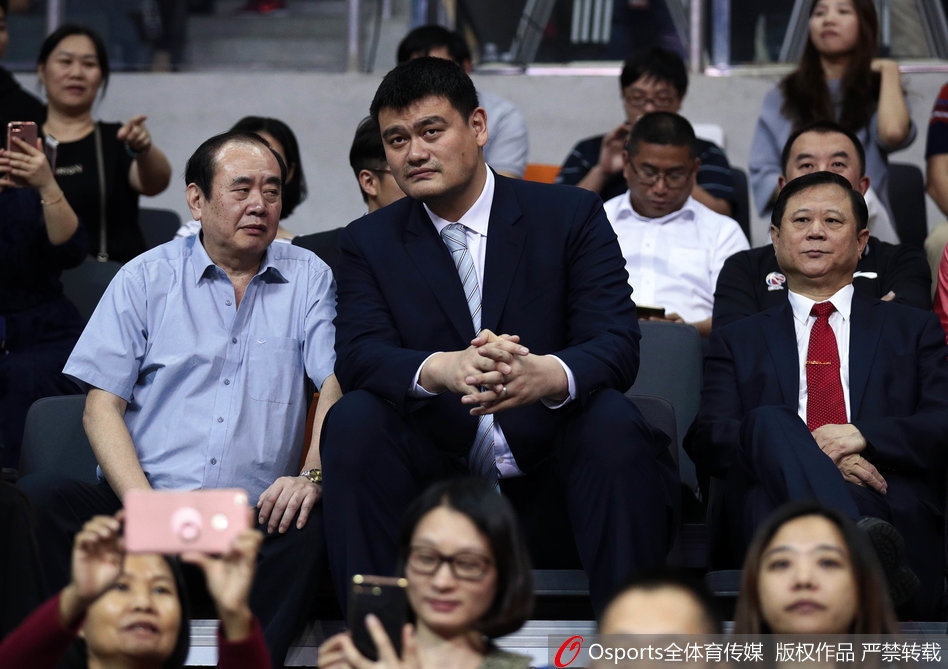 巨人俯瞰赛场，姚明与李金生在广东德比战看台上神情专注，目光如炬地审视着场上的每一次攻防转换。