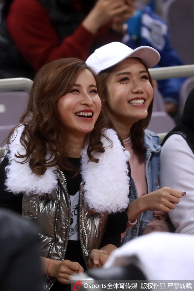 条纹衫女球迷在确认球队获胜后，绽放出阳光般灿烂的笑容，双手轻轻拢在身前，喜悦之情溢于言表。