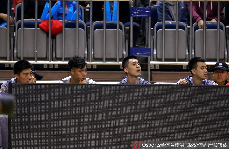 贺天举身穿休闲外套双手插兜,在场边目睹队友投中三分