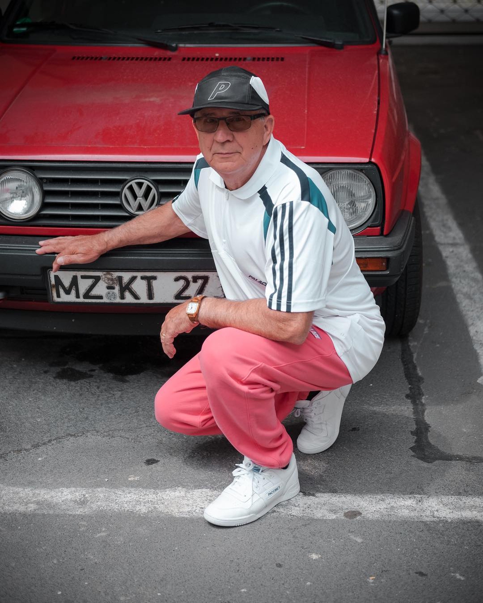 阿尔奥兹爷爷对于叠穿技巧运用得炉火纯青，深色牛仔外套内搭亮色帽衫，层次分明，即使站在复古机车旁，也透着股不羁的潮人风范。