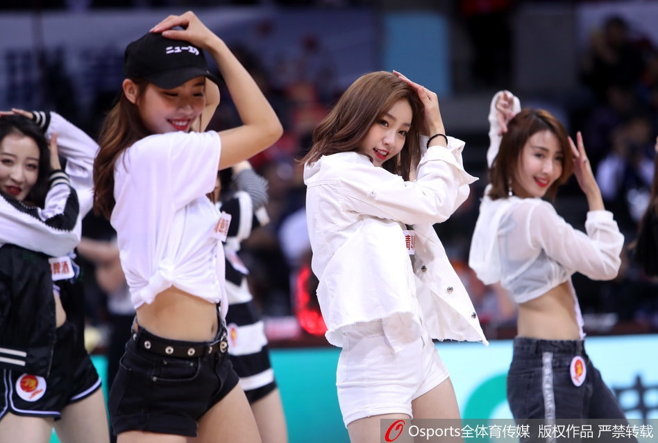 在动感的音乐节奏中，几名啦啦队员做出腾空跃起的动作，皮裤随着身体的延展在空中划出优美的弧线，她们的汗水在灯光下闪闪发光，展现了力与美的完美融合。