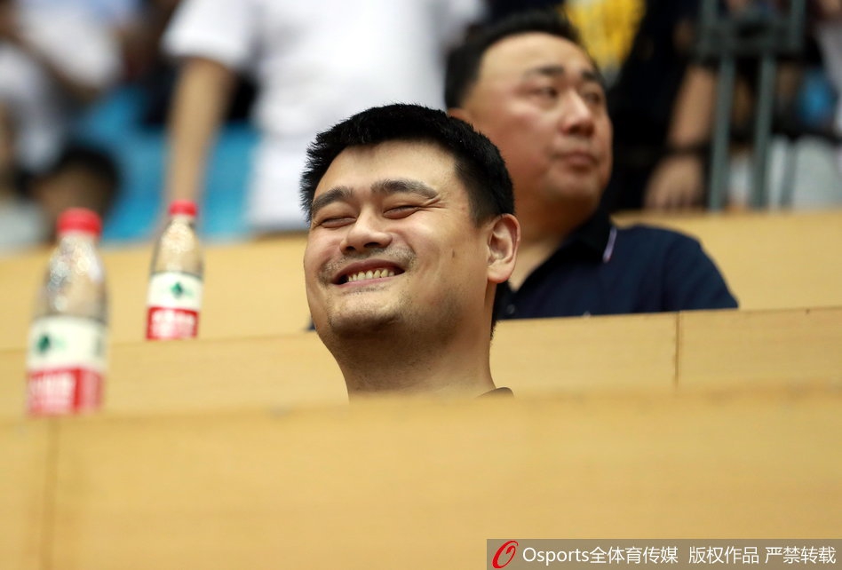 姚明神情专注地凝视着赛场，紧抿的双唇透露出内心的紧张与期待，仿佛在替场上的小伙子们使劲儿