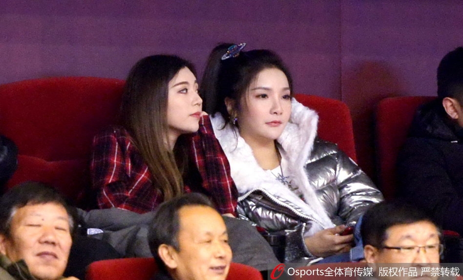 终场哨响，山东队获胜，两位闺蜜在看台上激动地拥抱在一起，喜悦之情溢于言表，身后是庆祝胜利的球迷海洋