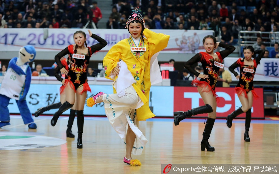 镜头拉近，一位篮球宝贝的妆容精致细腻，额头贴着戏曲特有的水钻，眼神中透露出既属于演员的英气又属于啦啦队员的活力，背景是模糊的球场灯光。