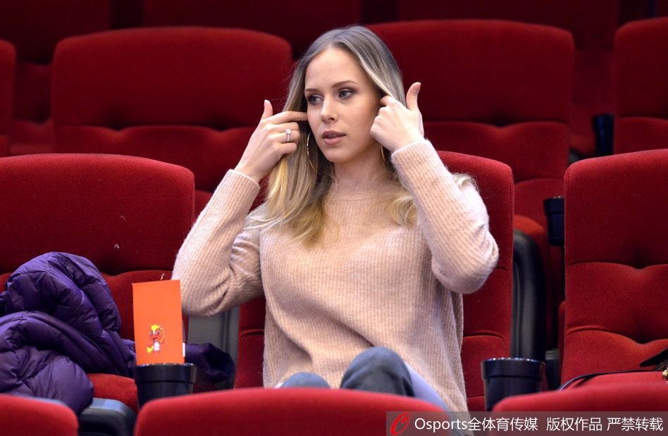 宝莲娜在观赛间隙低头查看手机,或许是在记录这场比赛的精彩瞬间,又或是在与无法到场的亲友分享此刻的喜悦,背景是模糊的球场和观众。