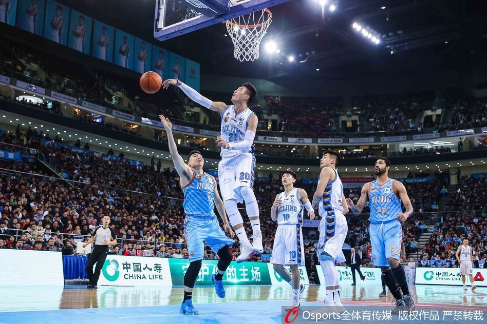 北京外援汉密尔顿在新疆内线群中高高跃起，单手抓球试图补扣，展现出惊人的臂展和制空权。