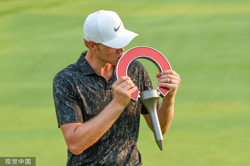 卡姆-戴维斯高举冠军奖杯，阳光洒在他灿烂的笑容上，背后是绿茵茵的球场和欢呼的人群。