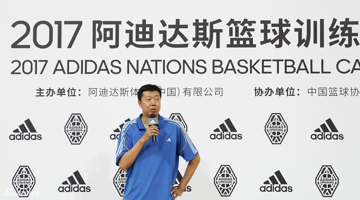 训练营的小球员们分组对抗,王治郅在场边叉腰观战,身后是醒目的阿迪达斯标志