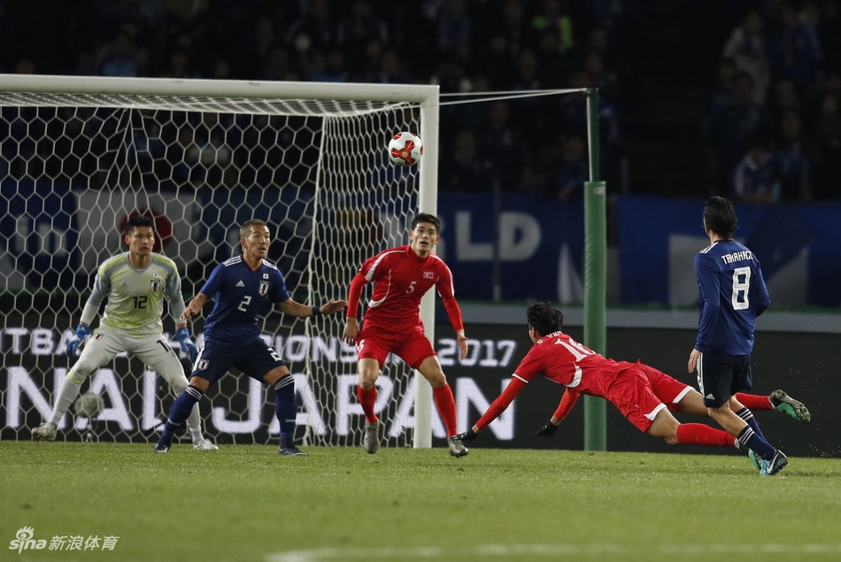东京冬夜寒风凛冽，朝鲜队球员如猎豹般迅猛地起脚攻门，日本队门将中村航辅横身舒展，指尖仿佛触碰到时间边缘，将必进之球拒之门外。