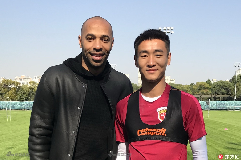 眼神中充满敬仰与渴望，年轻的韦世豪站在传奇巨星亨利身边，嘴角不自觉地上扬，仿佛正从眼前这位前辈的身上，汲取着关于顶级前锋的全部秘诀。