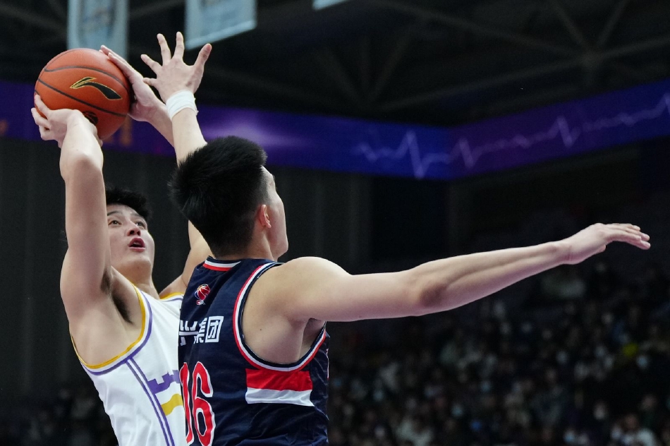 广州队年轻球员崔永熙眼神坚毅，在防守悍将的干扰下高高跃起完成高难度投篮，皮球在空中划过完美弧线