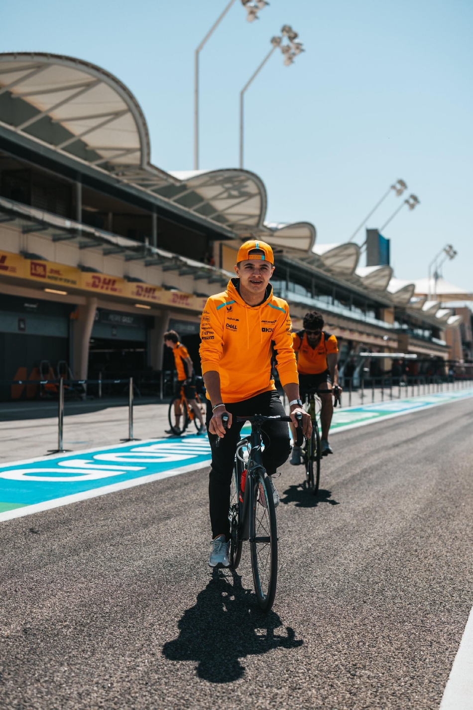 阿斯顿·马丁车队工作人员聚集在赛车旁进行最终战术简报,绿色的队服在灯光下连成一片充满希望的湖泊。