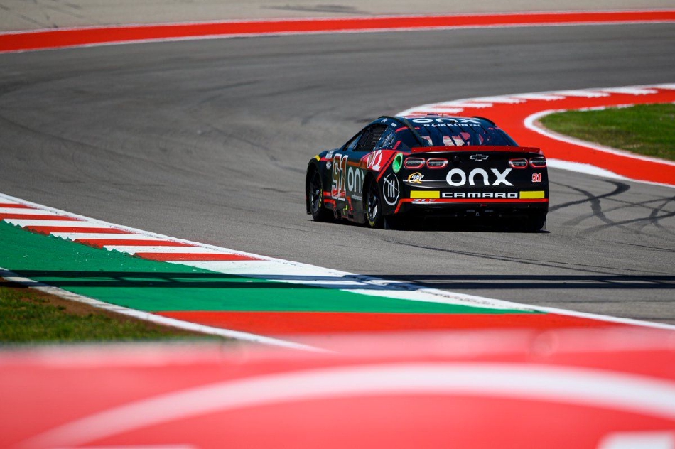 夕阳下,莱科宁的91号赛车驶过维修区通道,车身涂装在余晖中格外醒目,一旁的车队成员正密切关注着赛况。