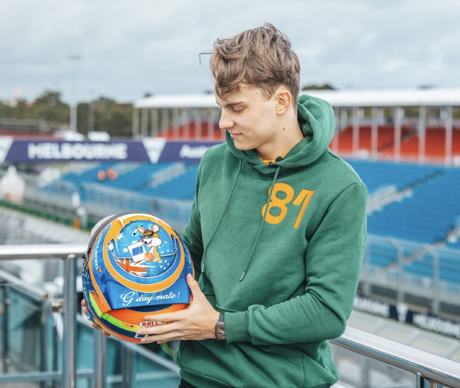 黄昏时分，阿斯顿马丁车队车库大门敞开，温暖的灯光照亮了即将投入战斗的赛车，与远处渐暗的天空形成鲜明对比。