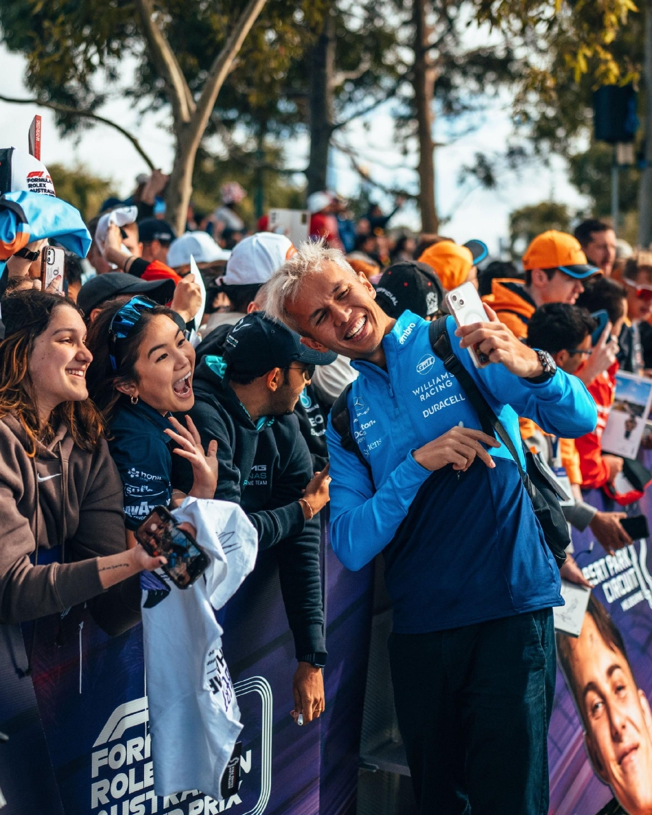 冠军车手站在赛车旁,手握头盔凝视远方,夕阳余晖为他与他的战车镀上一层金色的荣耀光辉。
