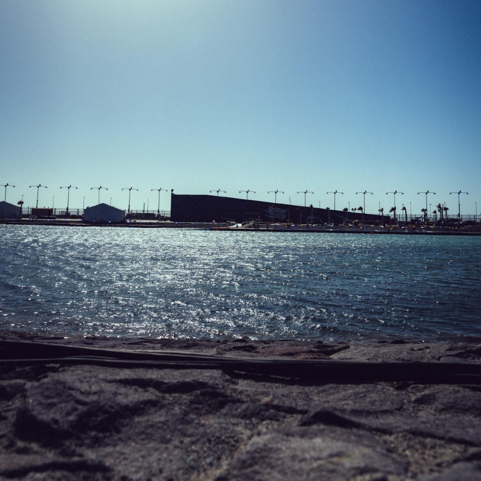 从高空俯瞰,维修区屋顶的弧形设计与赛道的锐利弯角形成几何构图之美,展现了现代F1赛事设施与竞技场地的完美结合。