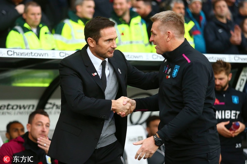 随着主裁判一声哨响，比赛正式开始。兰帕德双手插兜，目光如炬地凝视着场上的局势，而在不远处的客队教练席前，特里同样神情专注，认真观察着比赛进程，两人的身影在喧嚣的球场中构成一幅动人的画卷。