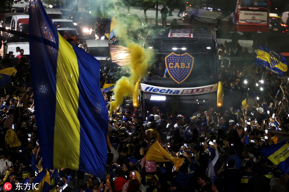 一名年轻的博卡球迷被父亲高高架在肩上，他的眼神穿越人群，紧紧锁定着远处的大巴。小小的脸庞上写满与年龄不符的坚毅与专注，仿佛要将这一刻深深烙印在心底，成为未来岁月里最骄傲的回忆。