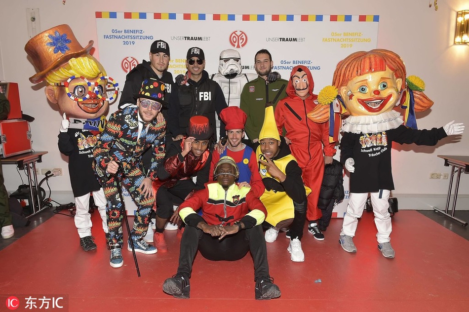 身披五色战袍的恐龙战队球迷摆出经典战斗姿态，背后的美因茨大教堂见证这趣味一刻。