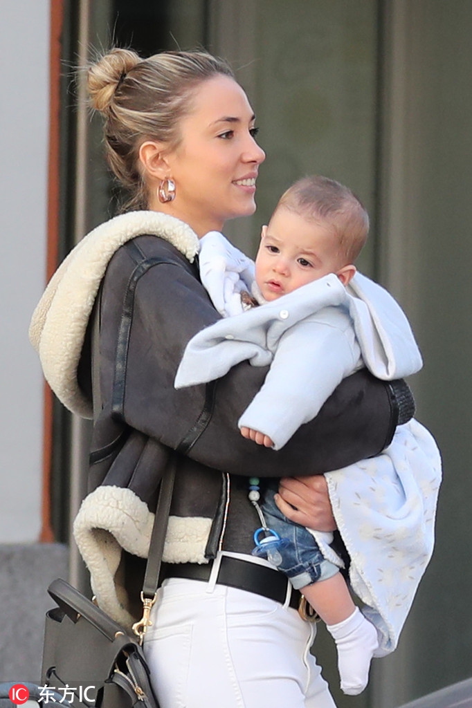 莫拉塔与爱丽丝在街头停下脚步，两人低头凝视婴儿车中的双胞胎宝宝，脸上洋溢着幸福满足的微笑。