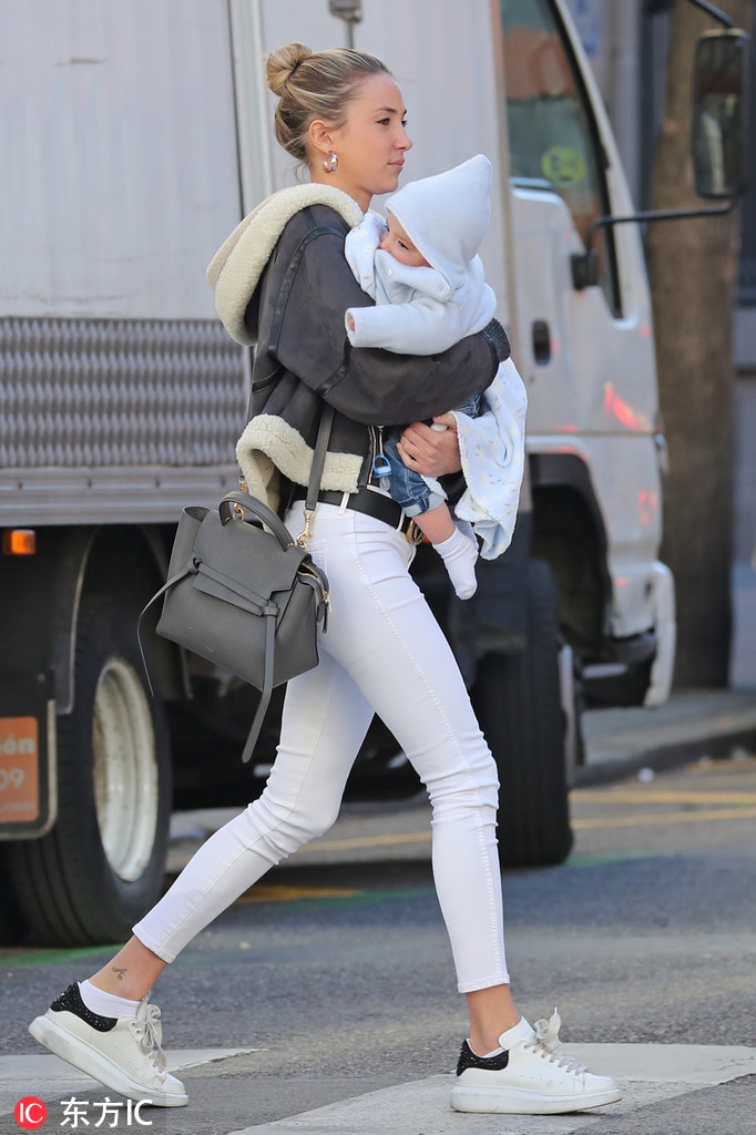 莫拉塔单手插兜走在前面，爱丽丝推着双胞胎婴儿车跟随，背景是马德里的城市街道，画面充满生活气息。