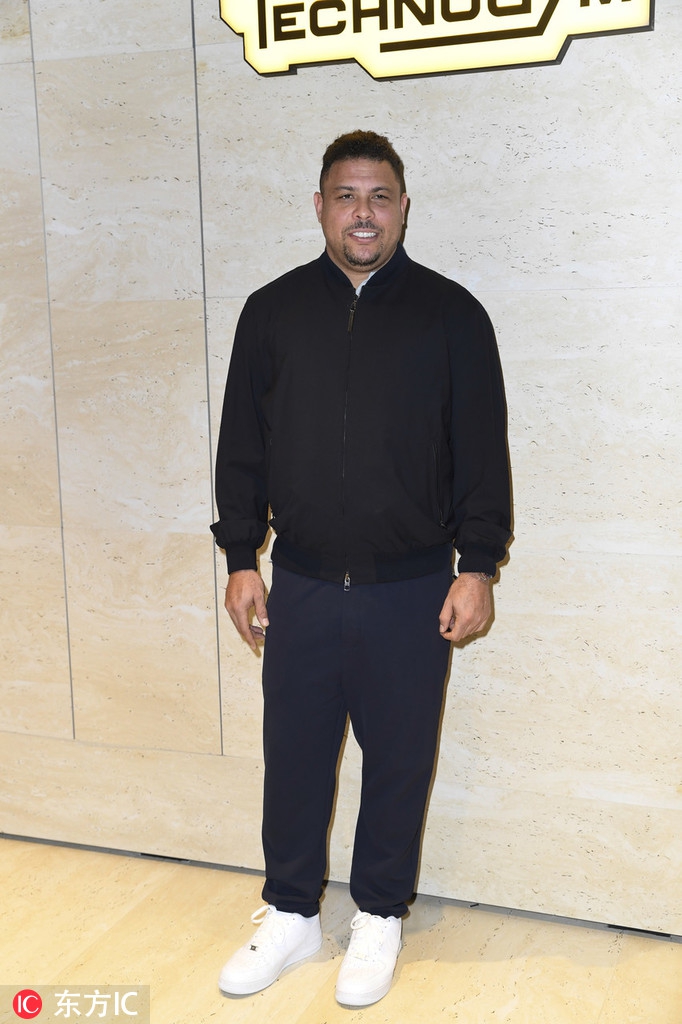 罗纳尔多在活动上手持物品，面带微笑，整个人透出一种从容富态的气质。