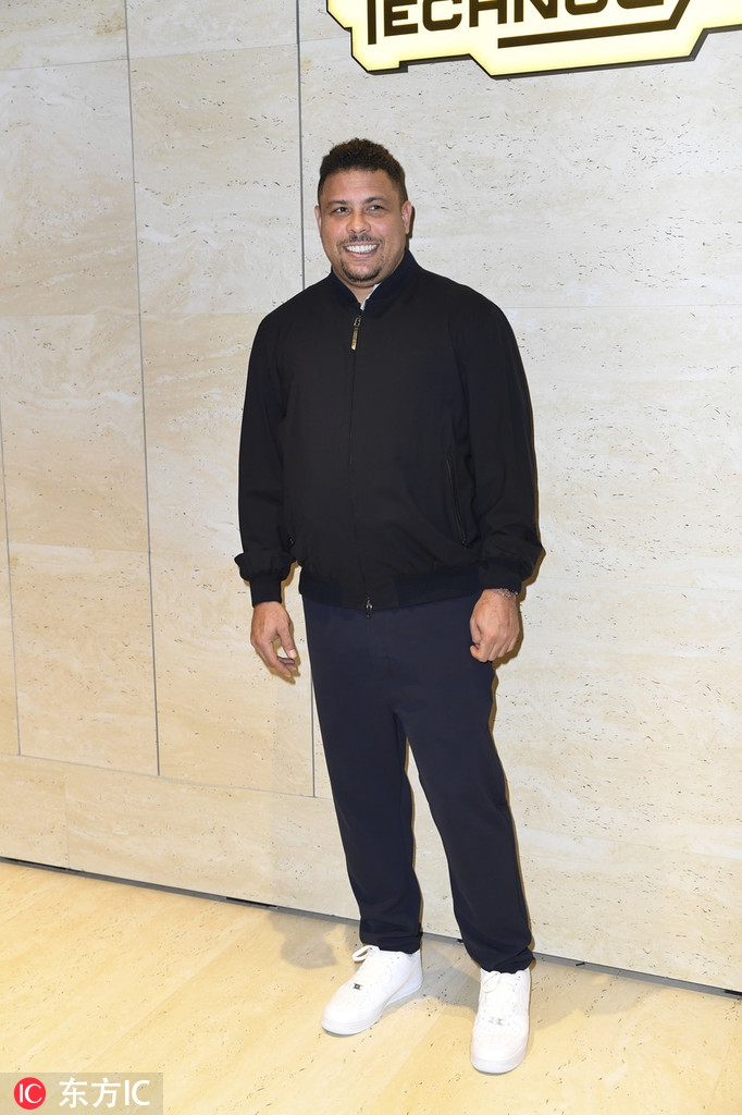 罗纳尔多侧身站立，脸上带着温和的笑意，双下巴清晰可见，但神态十分轻松自然。