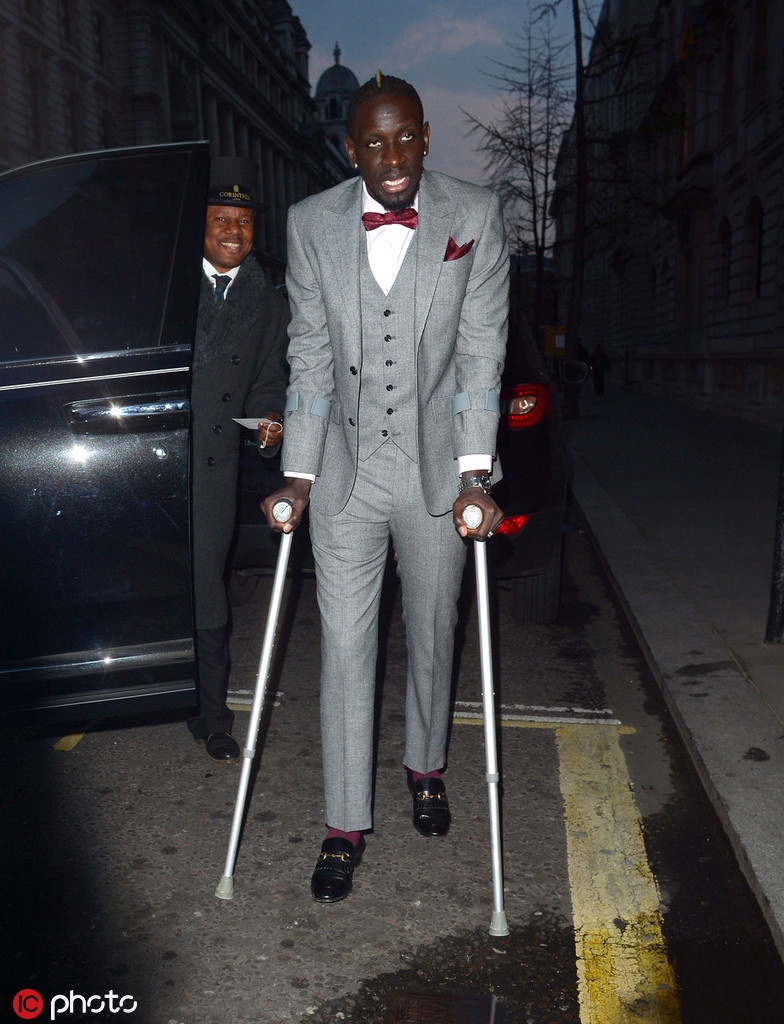 在晚宴的角落，萨科齐扶着双拐落座，眼神游离显得心事重重。周围的宾客觥筹交错，唯独他沉浸在自己的思绪中，仿佛与周遭的繁华隔绝。