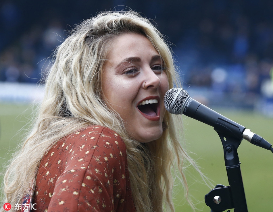 表演结束后，梅根-罗斯与身穿蓝色球衣的朴茨茅斯队员击掌互动，双方脸上都带着友好的笑容，气氛融洽