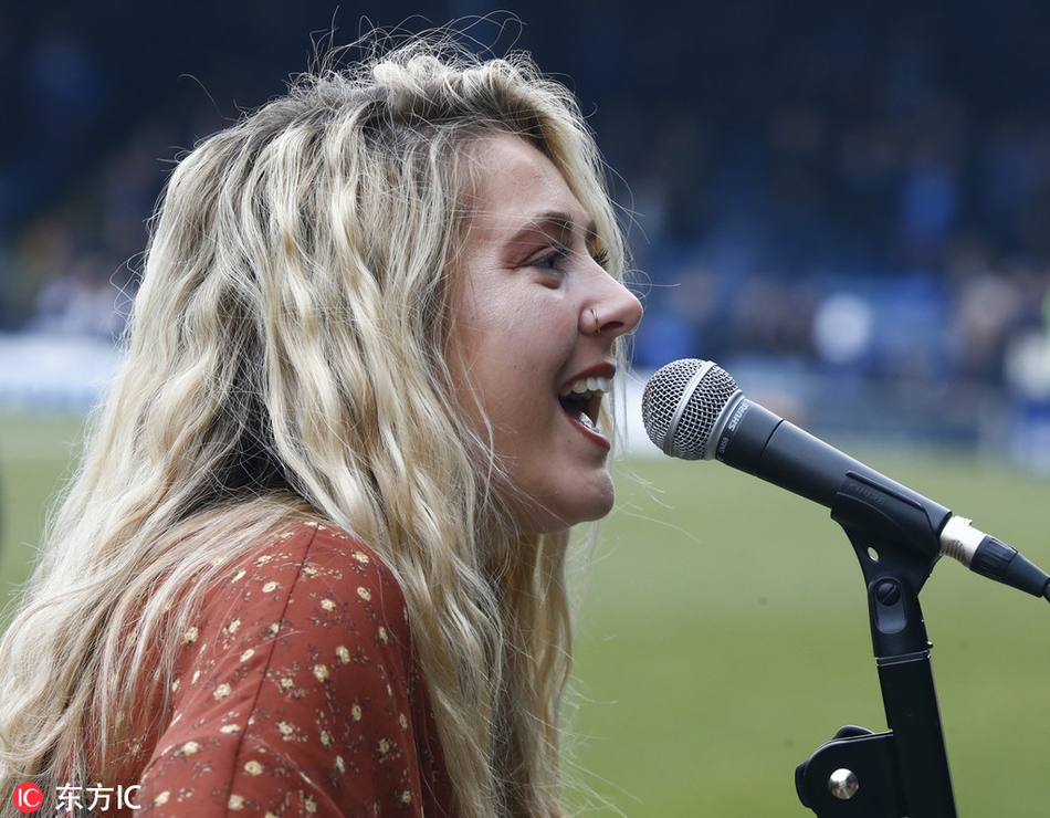 梅根-罗斯低头与身边可爱的小球童亲切交流，她微微俯身，眼神温柔，画面充满温馨与鼓励