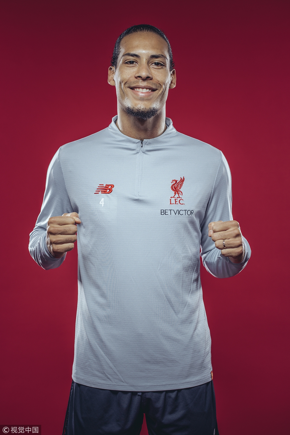 范迪克身着深色休闲装，倚靠在训练基地的围墙边，眼神望向远方，仿佛在回味刚刚结束的艰苦训练。