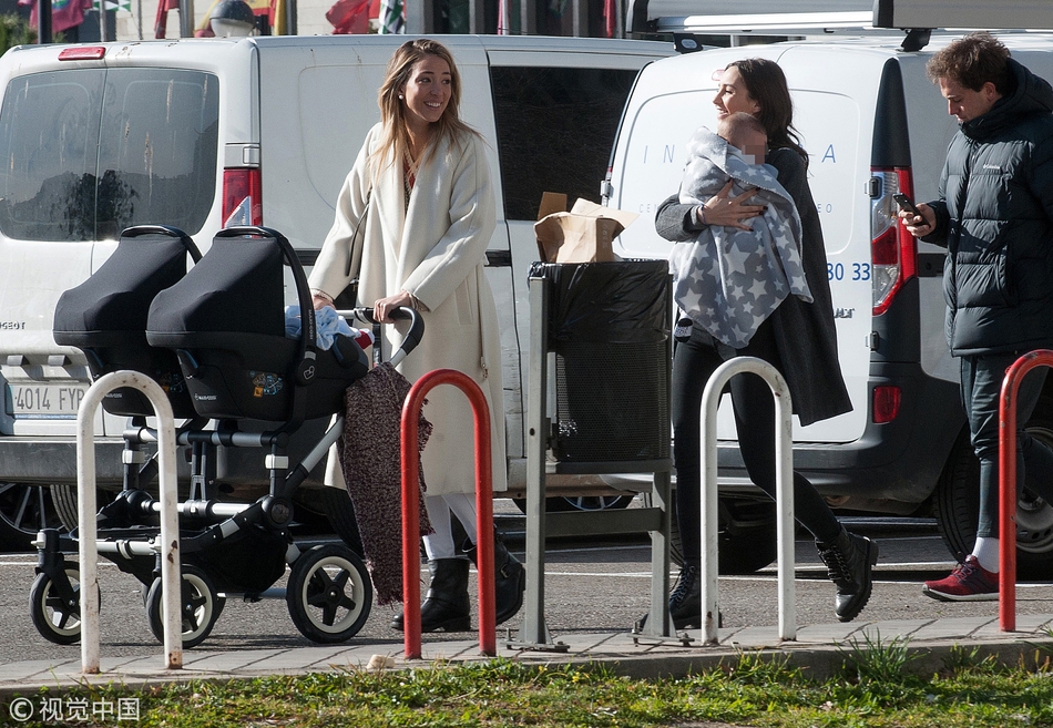 爱丽丝推着婴儿车走在马德里街头，她微微侧身查看孩子的情况，动作自然亲昵。简约的穿搭与周围的街景融为一体，展现出日常生活中的时尚感。