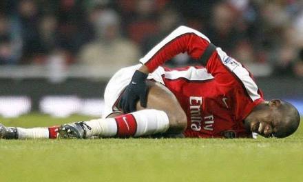 迪亚比痛苦地倒在草坪上，手捂着受伤的腿部，队友和队医迅速围拢过来，神情紧张