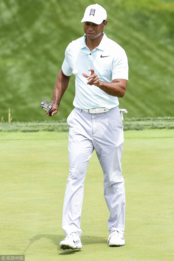 伍兹在练习果岭上轻推小球，动作优雅平稳，尽显千锤百炼的推杆技艺