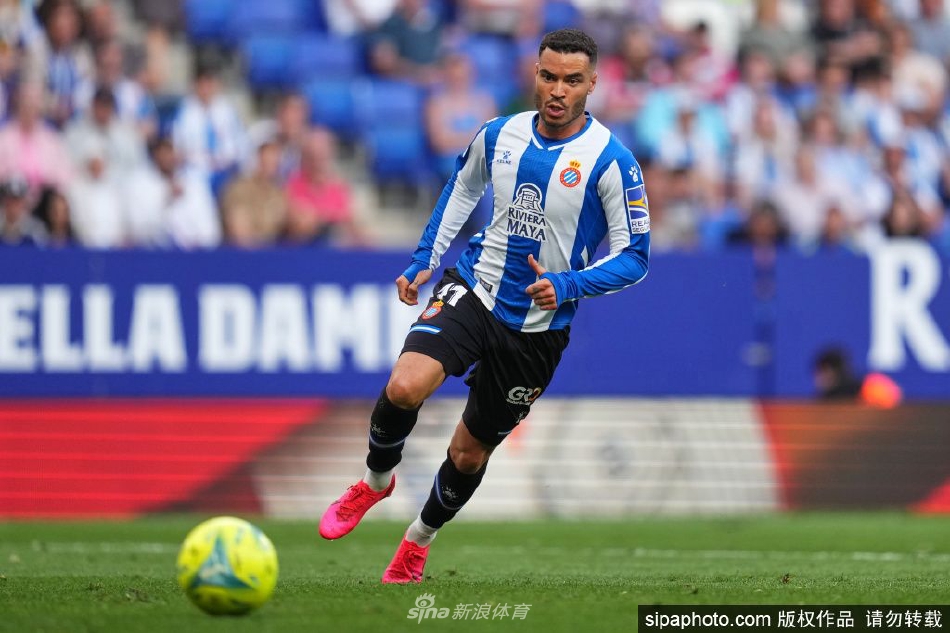 德托马斯手持巴列卡诺球衣，面带笑容站在主场球场中央，背景是欢呼的球迷看台