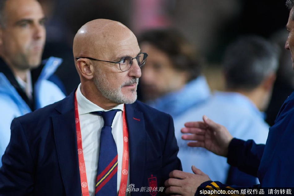 德拉富恩特与西班牙足协官员握手致意，背景是西班牙队徽，象征着责任与传承的正式交付