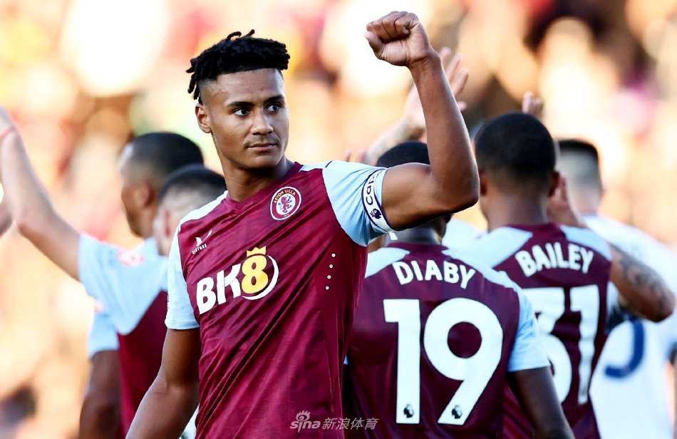 维拉公园球场全景，看台被热情的球迷填满，绿茵场在灯光下宛如一块巨大的翡翠，双方球员正在中圈准备开球，大战一触即发。