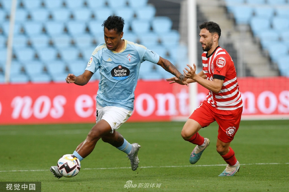 赫罗纳球员瓦列里·费尔南德斯在边路高速突破，塞尔塔后卫马略紧追不舍，看台上模糊的观众身影烘托出比赛的高速节奏