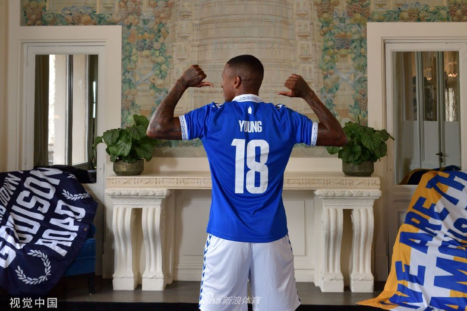 阿什利·扬在新闻发布会上展示印有自己名字的埃弗顿18号球衣，神情专注而自豪。