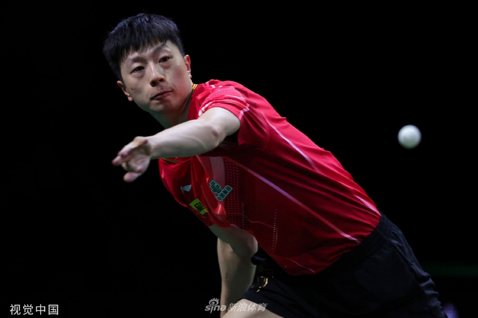 马龙在底线稳健防守，手臂肌肉线条分明，他将球优雅地回击至对面，白色的乒乓球在空中划出一道凌厉的弧线。