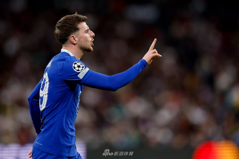 芒特在曼联更衣室内手持自己的新球衣，背景是红色的储物柜，标志着他已融入新环境