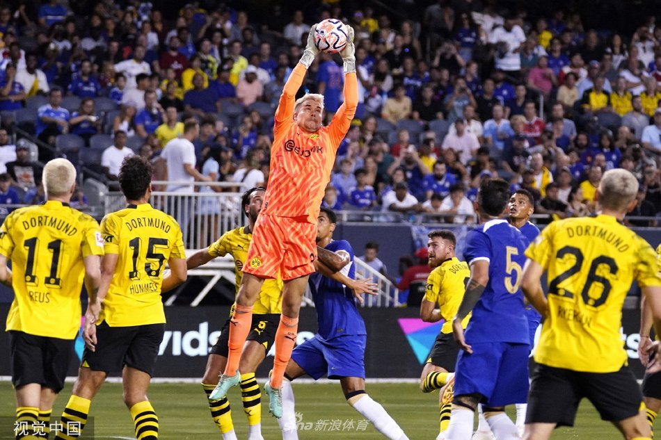 看台上切尔西与多特蒙德球迷比邻而坐，蓝色与黄黑色旗帜在夜风中交织飘扬，构成壮观的球迷画卷