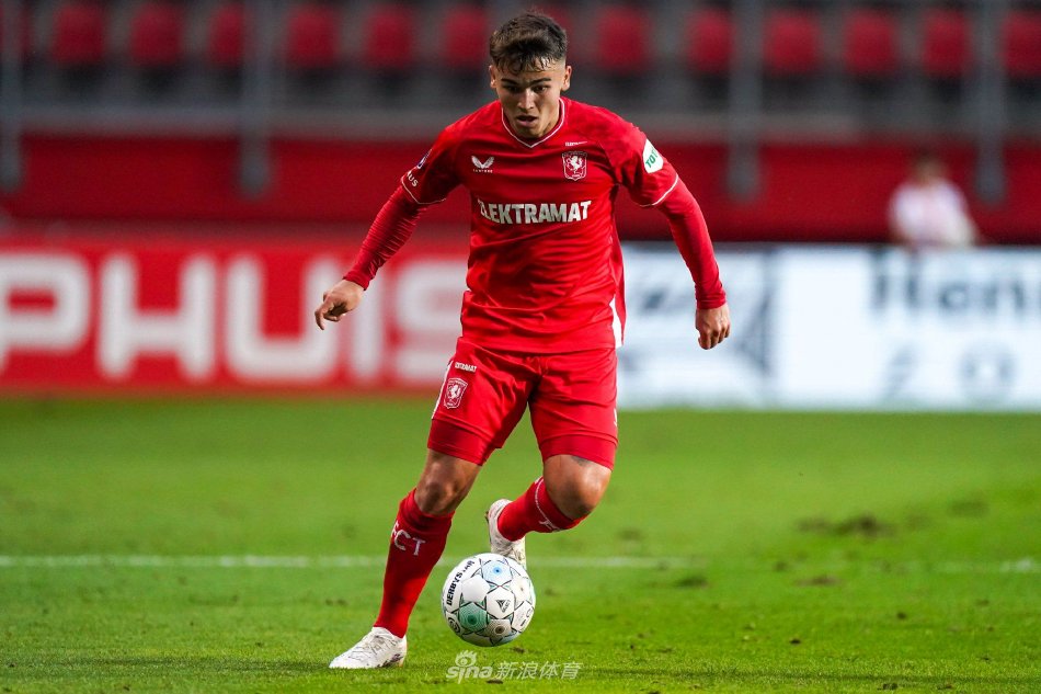 双方球员在中场展开激烈拼抢，足球在绿茵场上空划过一道弧线，球员们专注的神情与肌肉线条展现出足球运动的力与美