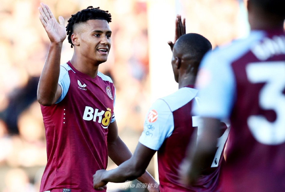 阿斯顿维拉球员激情庆祝进球，他张开双臂面向看台奔跑，身后是欢呼雀跃的队友，背景中可以看到拉齐奥门将失落地从球网中捡球。