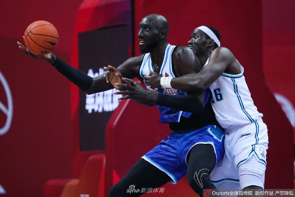 青岛队球员王睿泽在拼抢中倒地，但他第一时间抬头看向篮筐，眼神中充满不甘和对胜利的渴望，队友们纷纷上前准备拼抢篮板。