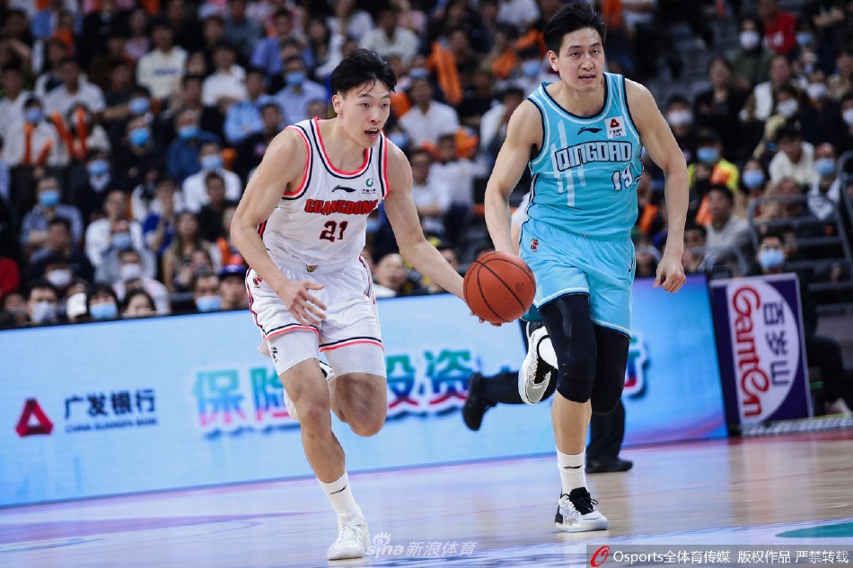 广东队与青岛队的球员们在场上激烈拼抢，篮球在多人手中争夺，瞬间的肌肉碰撞与专注的眼神，定格了比赛的激烈程度。