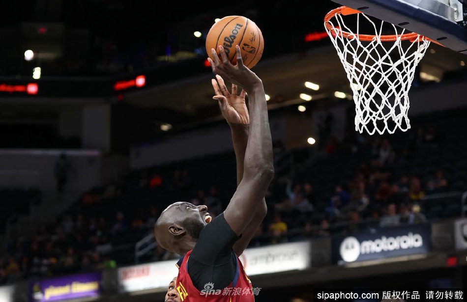 训练场上，塔科·法尔微微侧头倾听，眼神专注而柔和，仿佛正在认真理解教练的战术布置。他那远超常人的巨大体型，在普通的篮球场地上显得格外醒目，宛如一座移动的高塔。