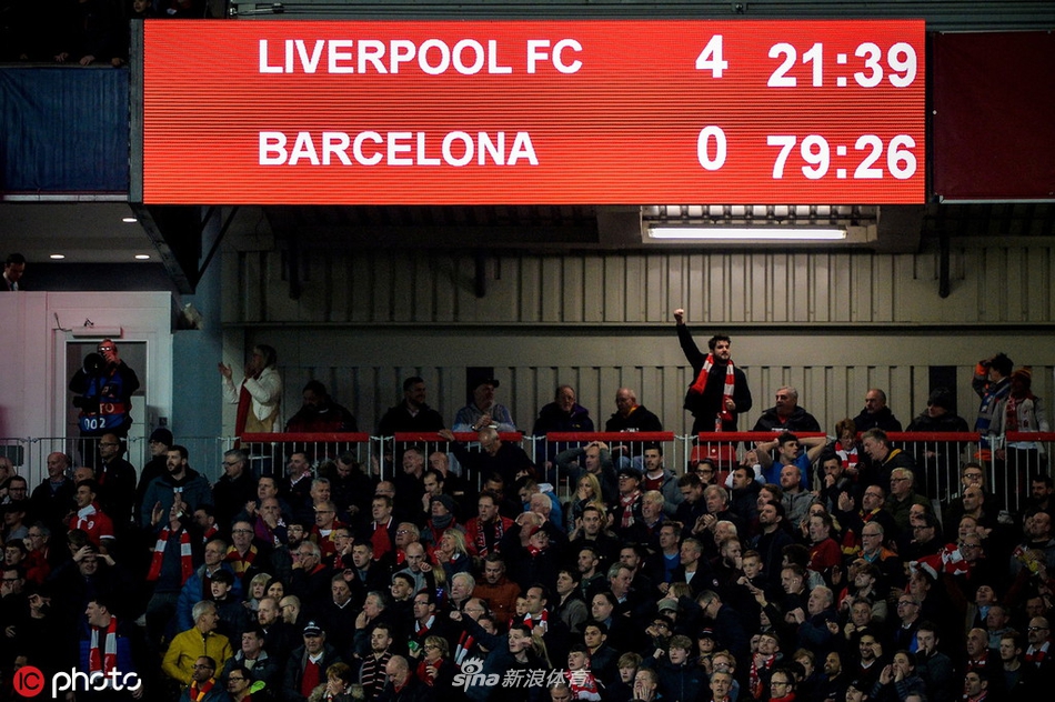利物浦全体球员在赛后紧紧相拥，围成一圈庆祝这来之不易的胜利，背景是巨大的记分牌，象征着团队的凝聚力和伟大成就。