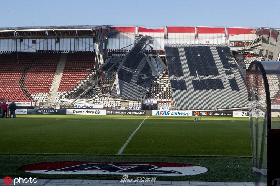 从高处俯瞰，坍塌的屋顶在蓝色座椅上撕开了一道巨大的白色伤口，扭曲的金属框架和破碎的板材相互纠缠，仿佛刚经历了一场地震。